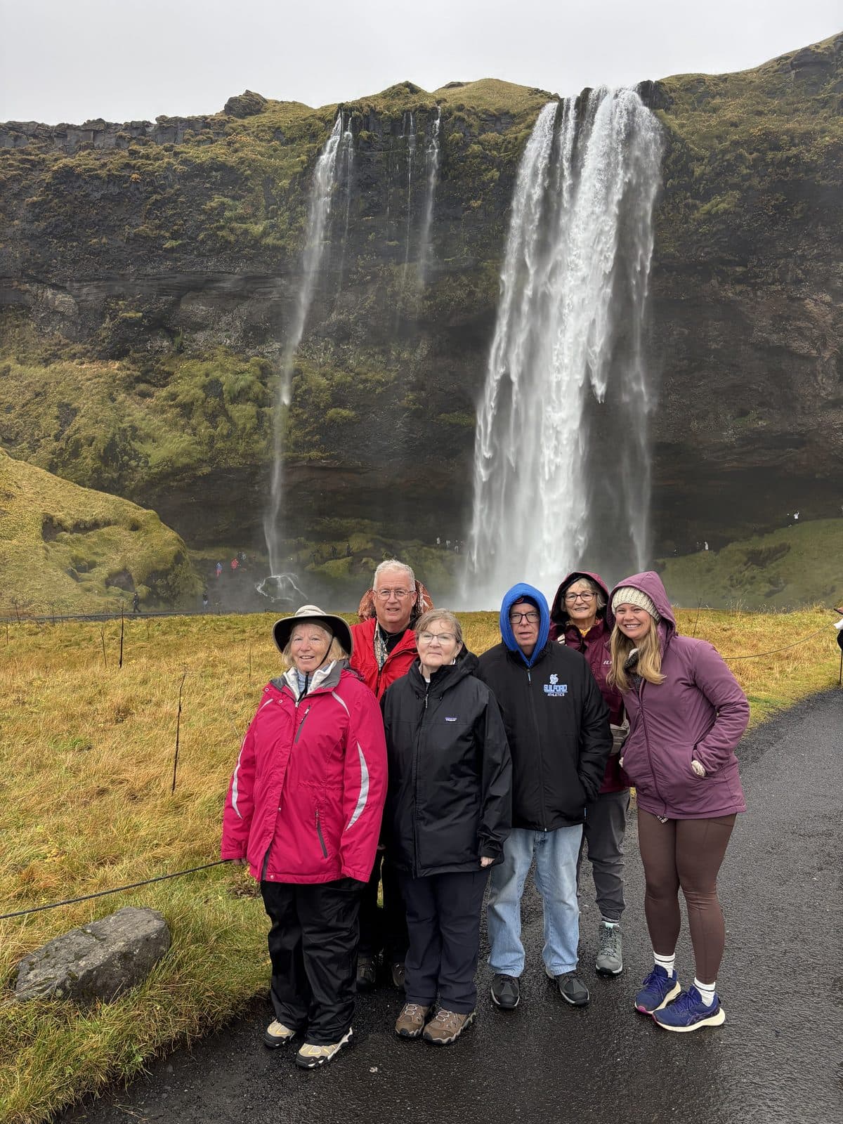 Tom's Christian Tours travelers standing together in front of a waterfall